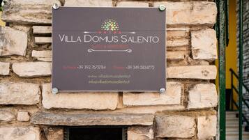 A sign for Villa Domus Salento Suites & Apartments with contact information and website URLs.