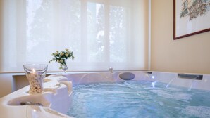 A hot tub with a clear glass vase of flowers and a candle, near a window with sheer curtains. - Villa Domus Salento Suites & Rooms (Lecce)