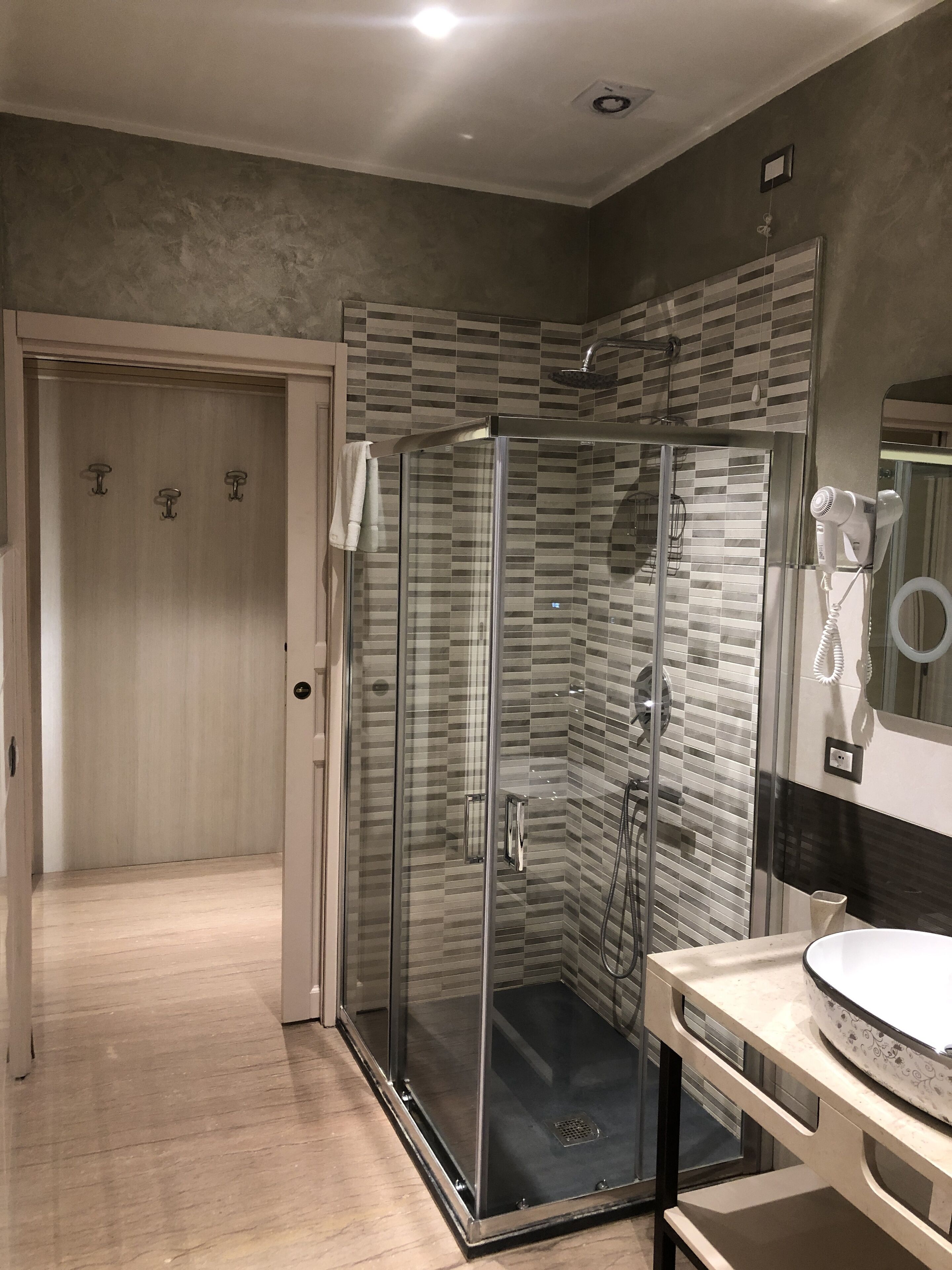 A modern bathroom with a glass-enclosed shower, a vanity with a mirror, and a towel rack.