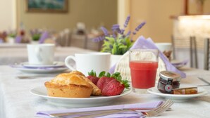 A breakfast setting with a muffin, strawberries, a glass of red juice, and a jar of jam on a table. - Villa Domus Salento Suites & Rooms (Lecce)