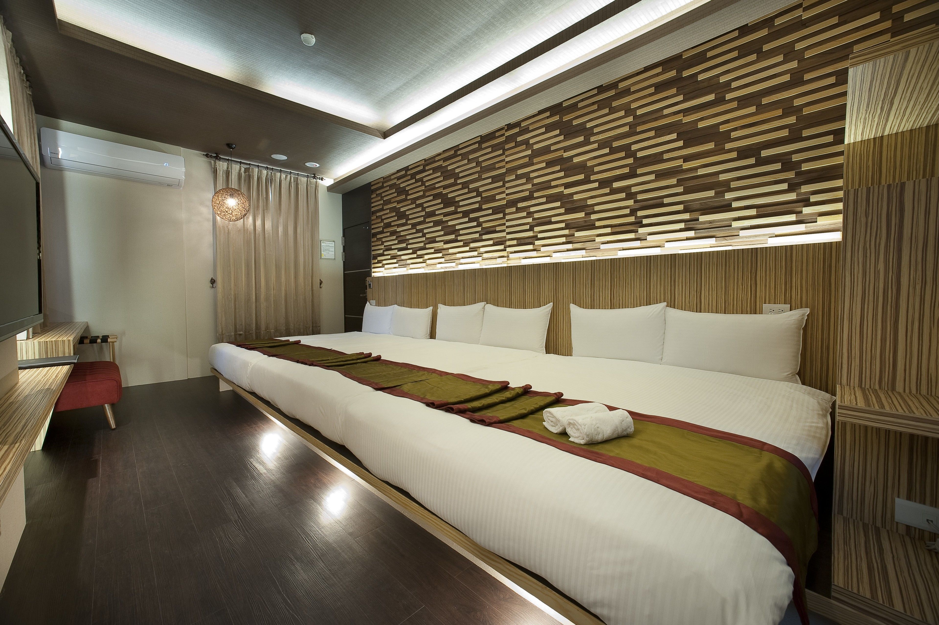 Habitación de hotel moderna con una cama grande, panel de pared de madera y un pequeño escritorio con silla.