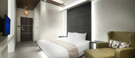 A modern hotel room with a large bed, a sofa, a television, and a dark accent wall.