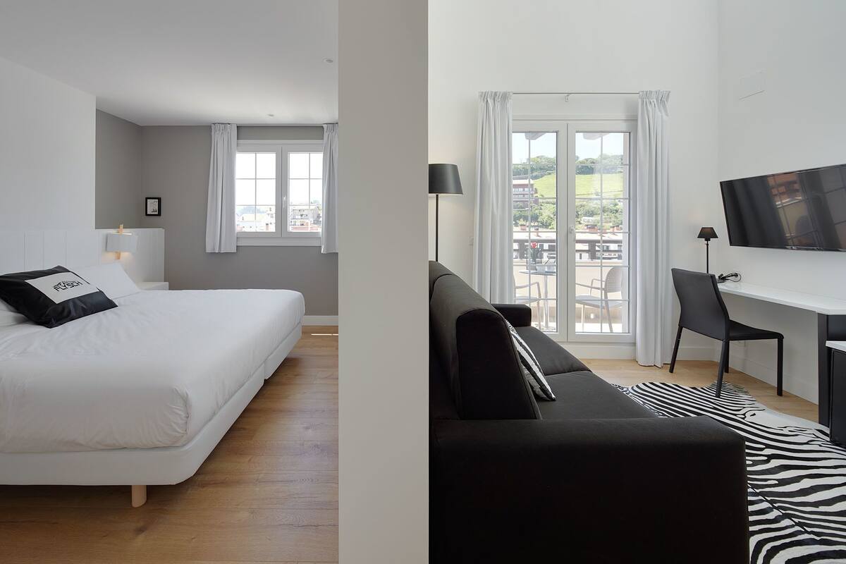 Une chambre d’hôtel avec un lit, un bureau et une chaise, une télévision et un balcon avec vue.