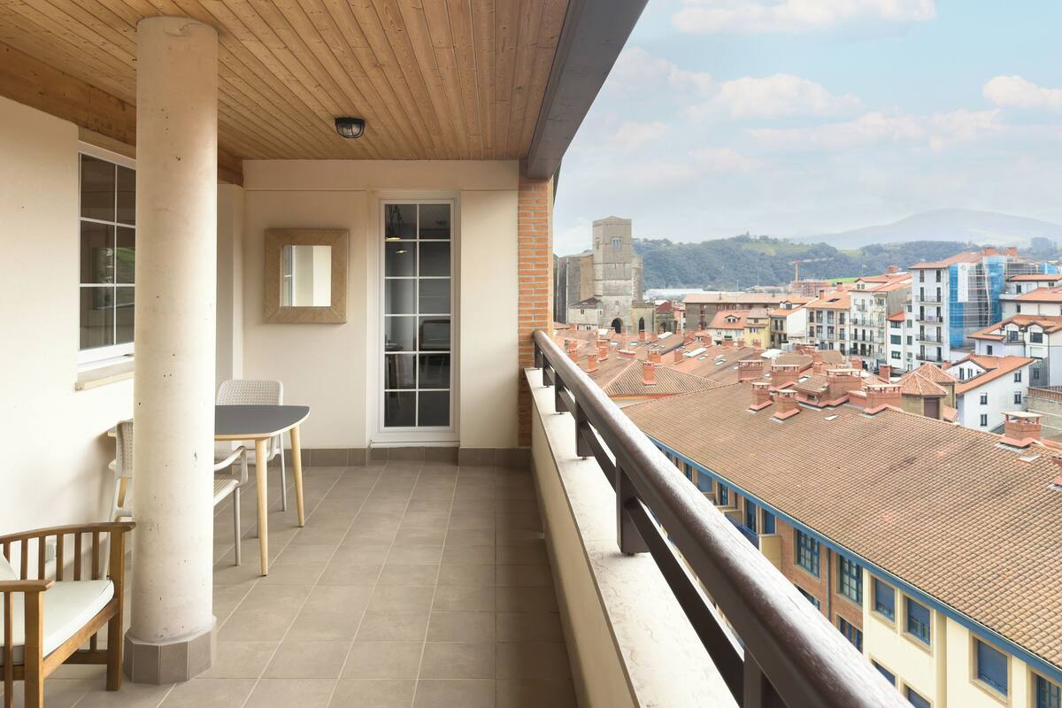 Un balcon donnant sur la ville, une table, des chaises et une fenêtre.