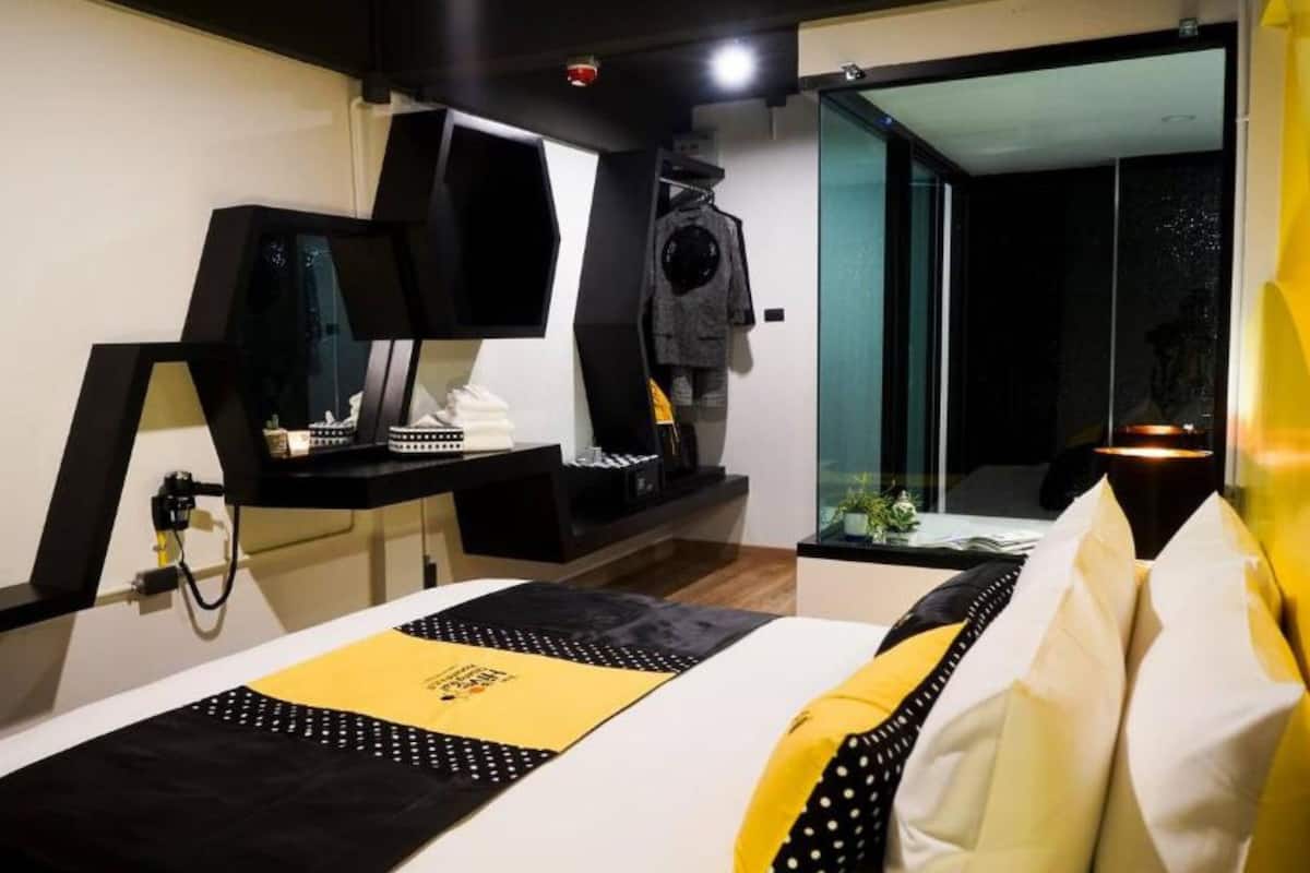 Una habitación de hotel moderna con una cama, un escritorio, un televisor y vistas al exterior.