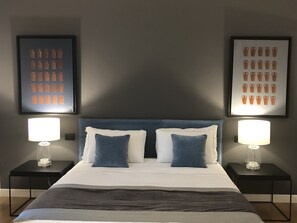 A neatly arranged hotel room with a large bed, two bedside tables with lamps, and two framed pictures on the walls. - LeMummarelle76 (Naples)