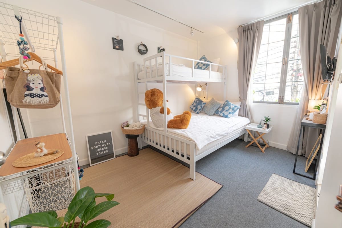 A bunk bed room with a small table, a basket, and a plant.