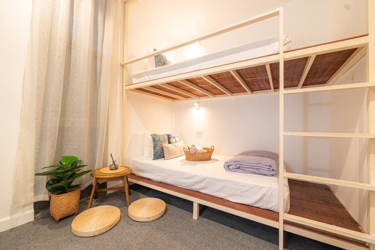 A bunk bed room with a small table, a potted plant, and a basket on the bed.