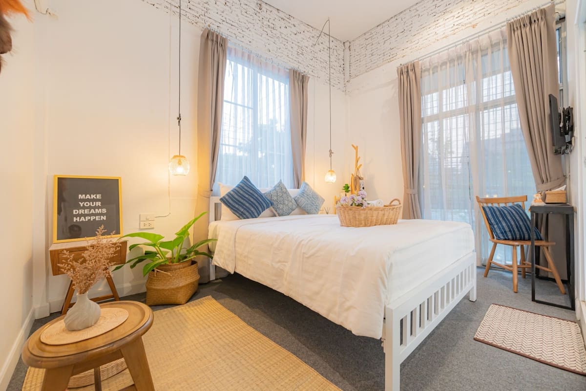A neatly arranged bedroom with a bed, bedside tables, a chair, and a desk.