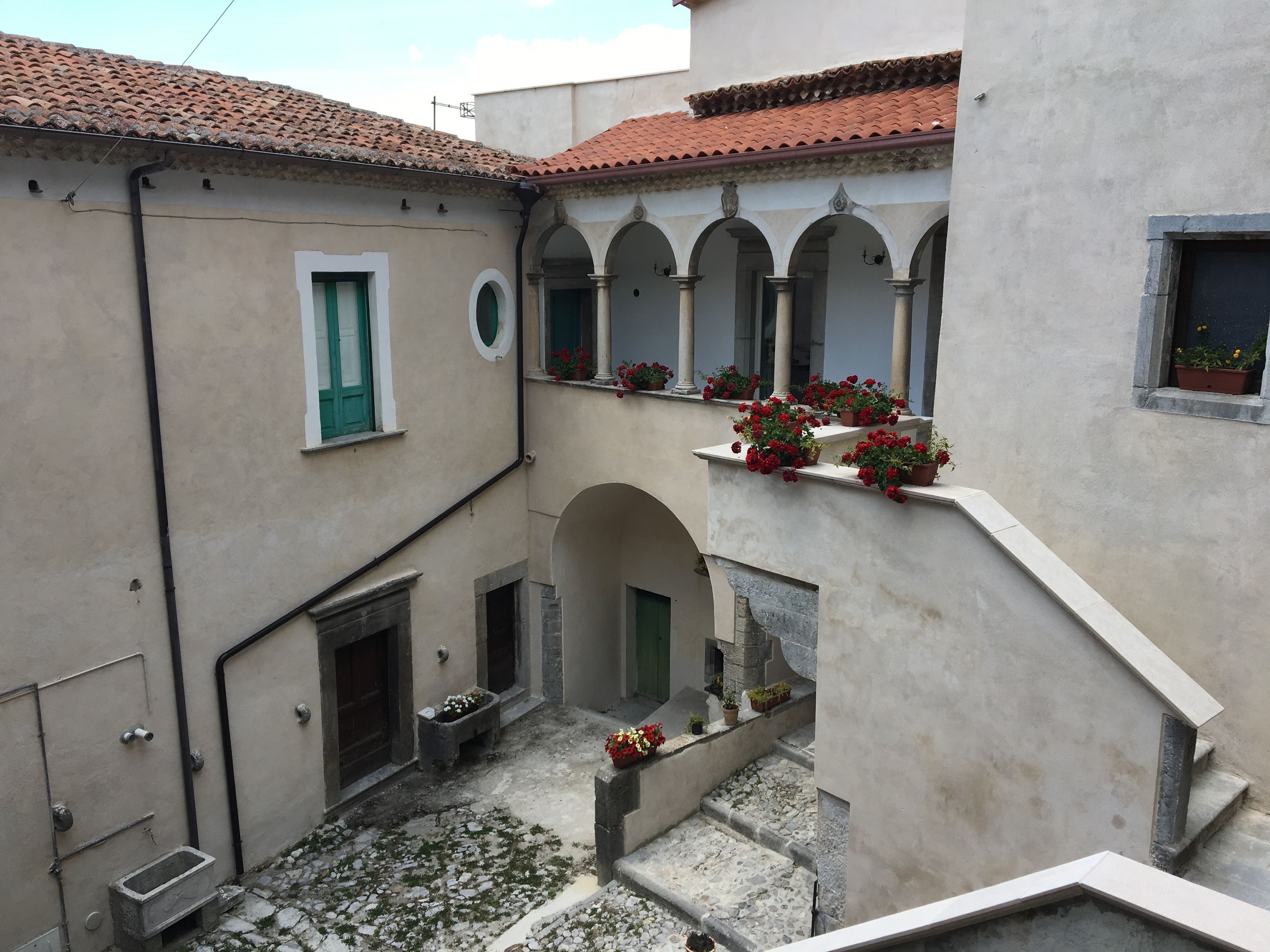 A courtyard with a tiled roof, arched doorways, and potted plants.