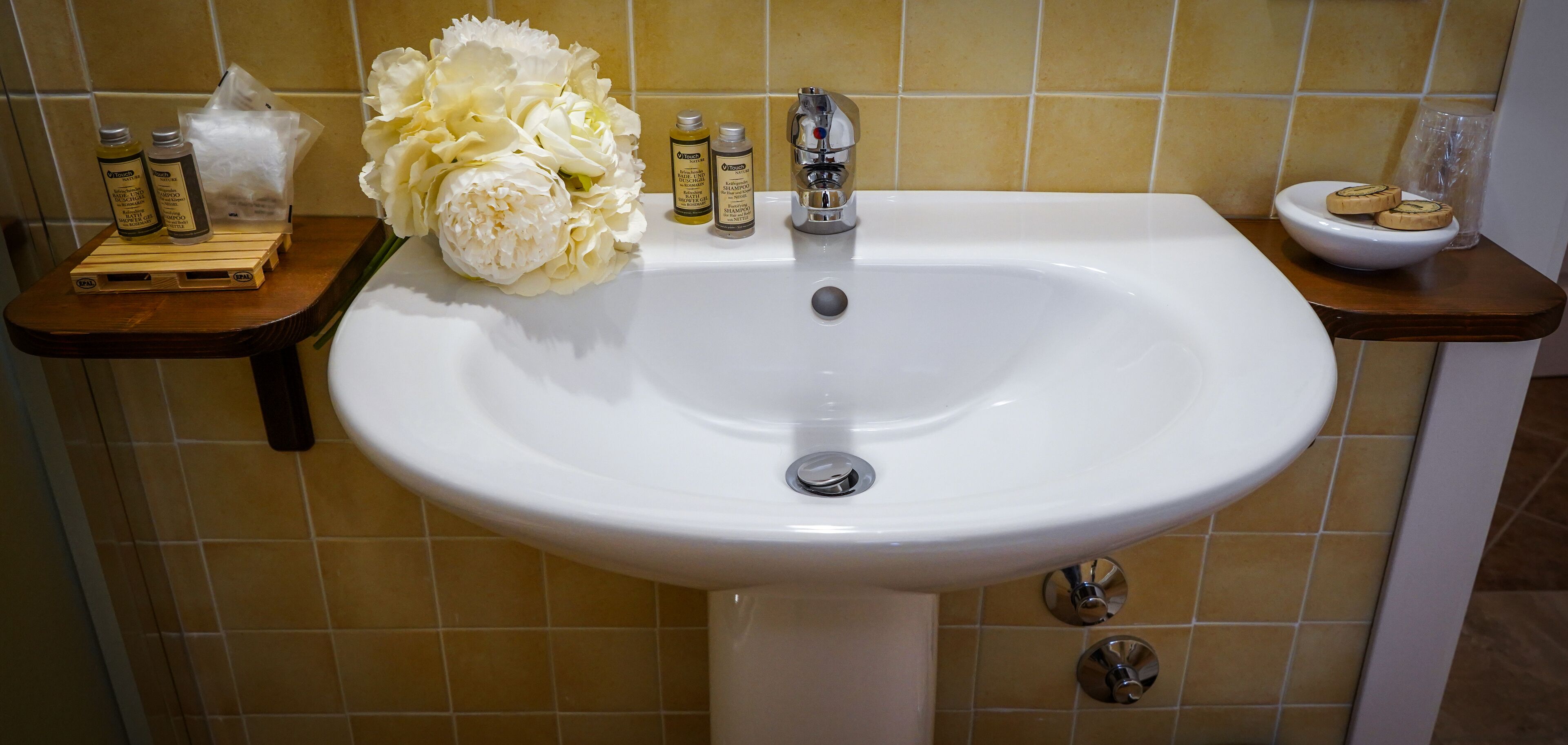 A bathroom sink with toiletries and a bouquet of flowers.