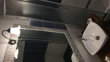 Un baño con espejo, lavabo y piso de baldosas.