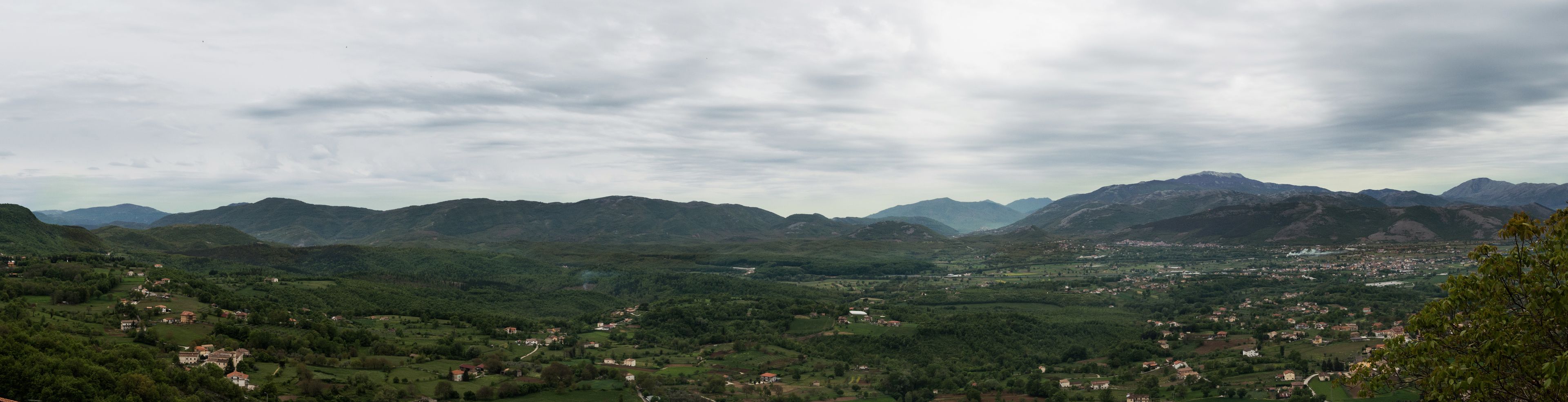 Eine gebirgige Landschaft mit einem Tal und verstreuten Gebäuden.