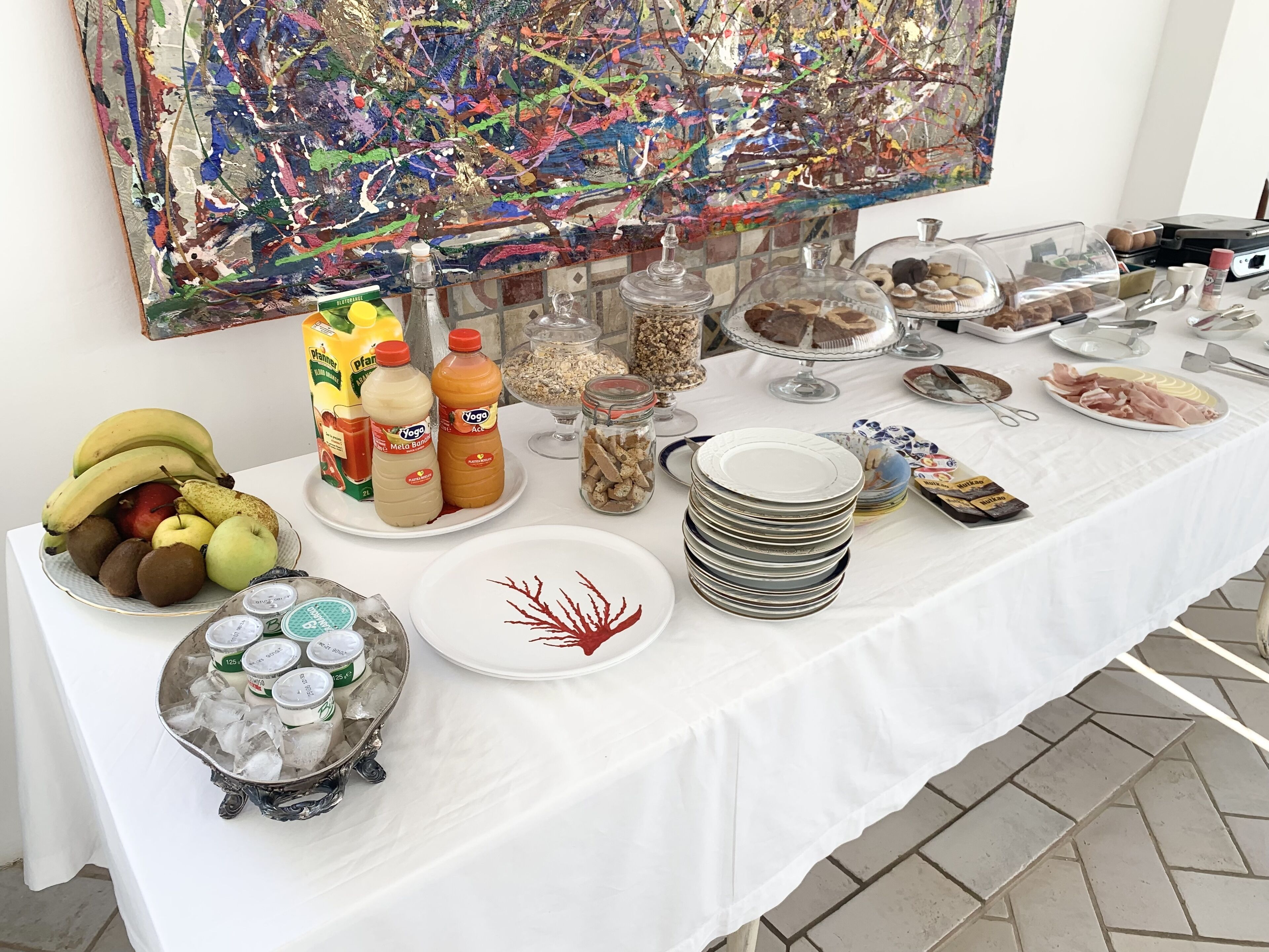 A buffet table with various food items, including fruits, beverages, and condiments.