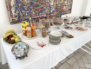 Ein reichhaltiges Buffet mit verschiedenen Speisen, darunter Obst, Getränke und Beilagen.