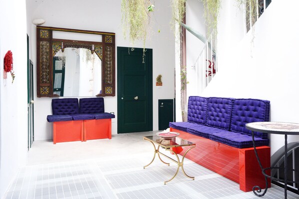A room with a green door, a purple sofa, a red bench, and a glass coffee table. - Salapolis Luxury Apartments (Gallipoli)