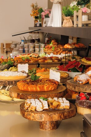 A buffet with various desserts and pastries on wooden stands. - Villa Augustea (Rimini)