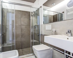 A modern bathroom with a glass-enclosed shower, a white sink, and a toilet. - Villa Augustea (Rimini)