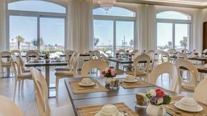 A dining area with tables set for service, large windows, and a chandelier. - Villa Augustea (Rimini)
