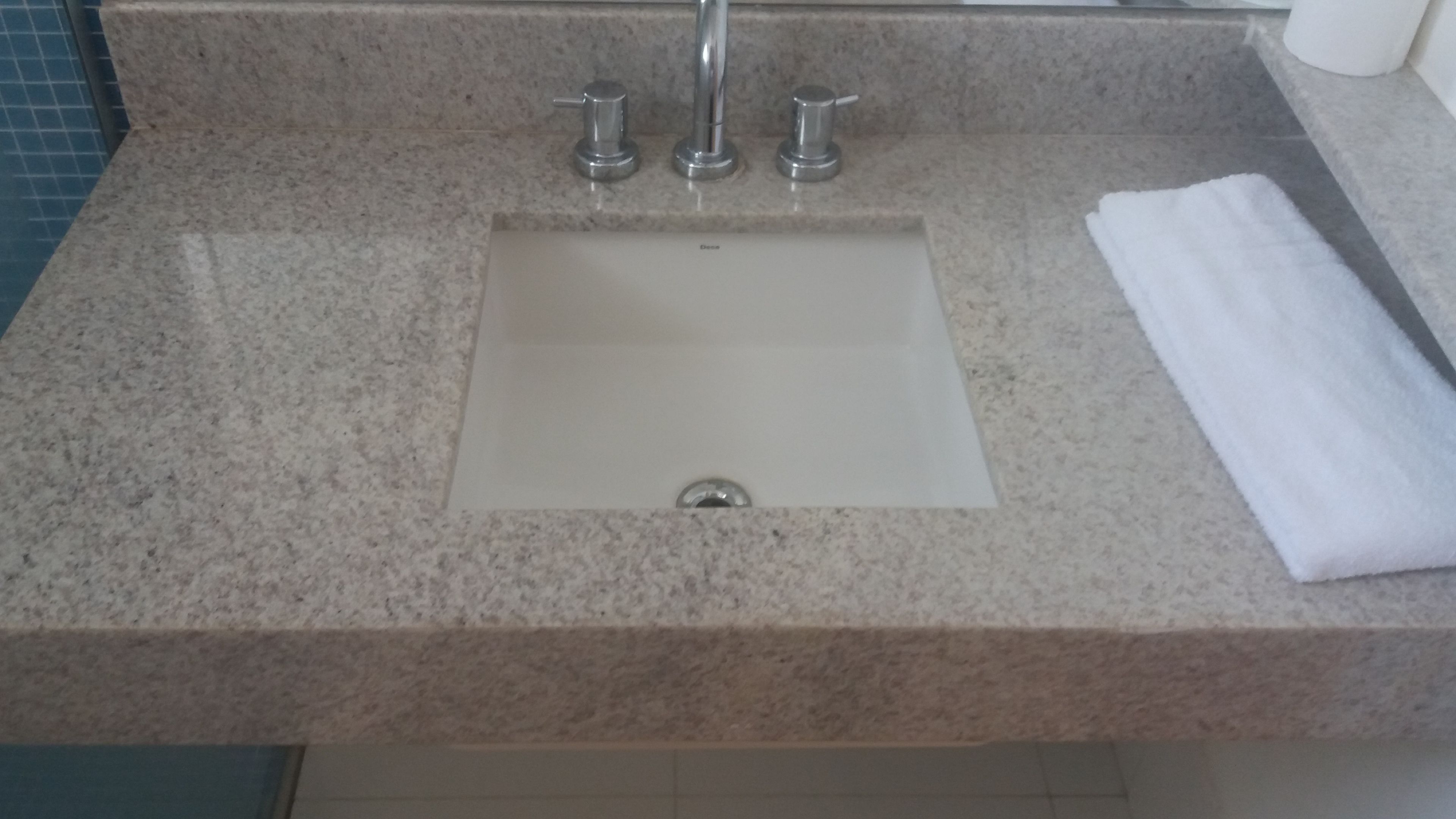 A bathroom sink with a marble countertop, a single faucet, and a white towel on the right.