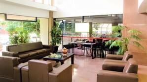 Un vestíbulo amplio con un sofá, sillas, una mesa de centro y un área de comedor con mesas y sillas.