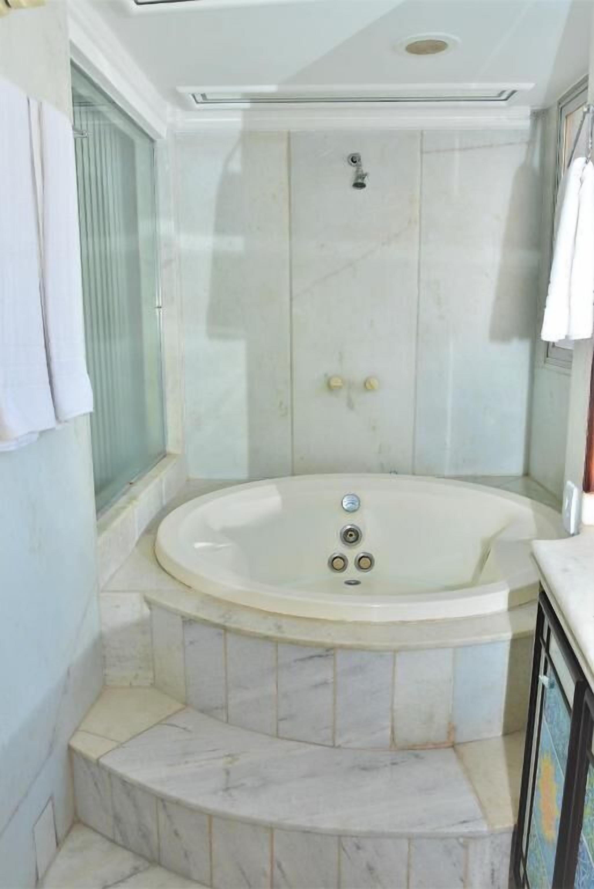 A modern bathroom with a freestanding bathtub, a glass shower enclosure, and a marble-tiled floor.