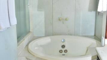 A modern bathroom with a freestanding bathtub, a glass shower enclosure, and a marble-tiled floor.
