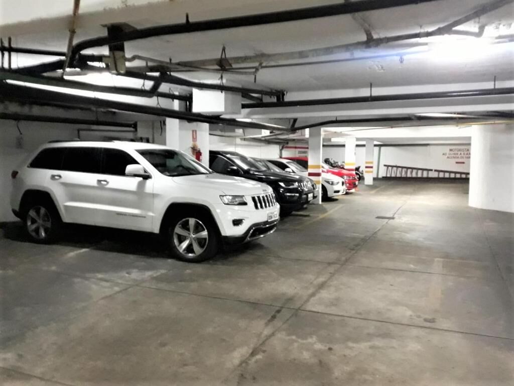 A parking garage with multiple cars parked in rows.