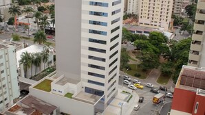 Un edificio alto con terraza plana, rodeado de otros edificios y una calle concurrida.