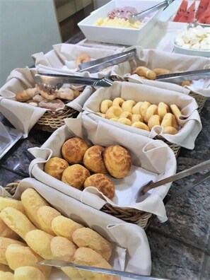 Un bufé con diversos productos de panadería, incluyendo panes y pasteles.