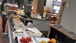 Una barra de buffet con diversos alimentos, entre ellos frutas, verduras y salsas.