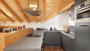 Une cuisine moderne avec des poutres en bois au plafond, un four Bosch et un plan de travail en granit.