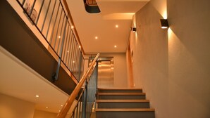 Un escalier moderne avec des marches en bois et des rampes en métal, menant à l’étage supérieur.