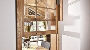 Une pièce dotée d’une grande fenêtre à cadre en bois, d’une table en bois et d’un luminaire suspendu.
