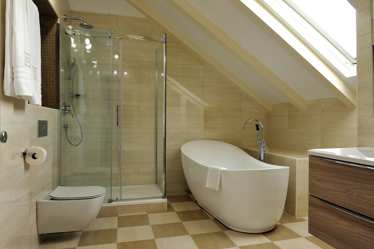 A modern bathroom with a glass-enclosed shower, a freestanding bathtub, and a toilet.