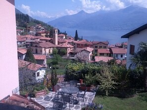A residential area with houses, a patio with outdoor furniture, and a mountain in the background. - Balcone Fiorito Bed & Breakfast (Menaggio)