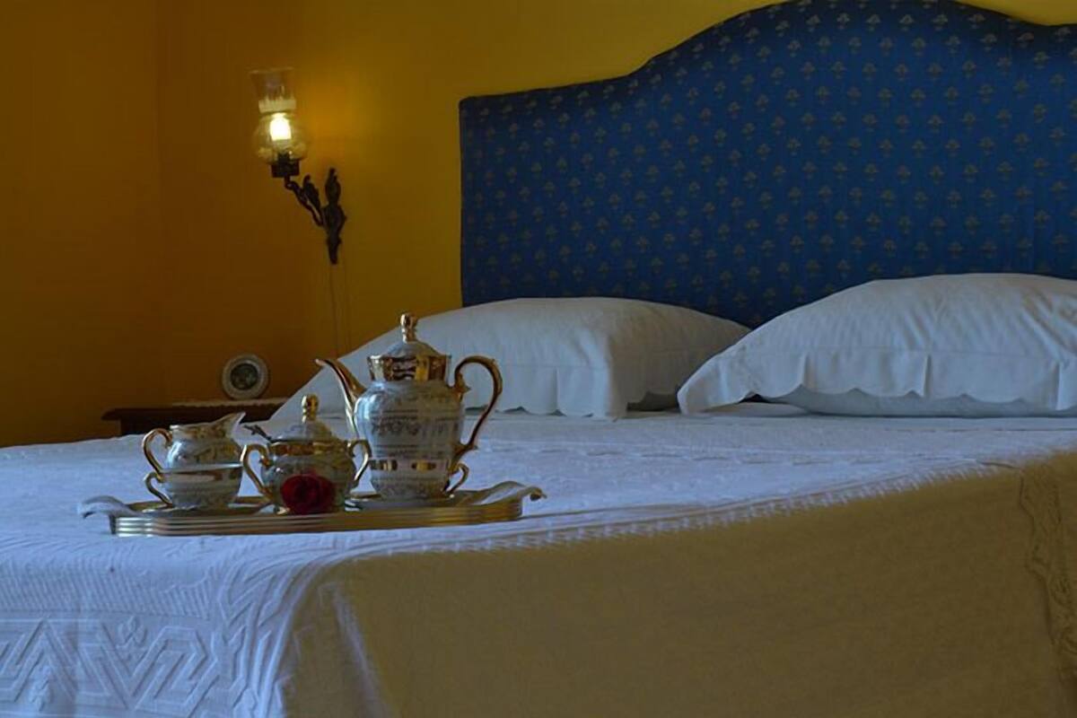 A neatly made bed with white linens and a tray of tea service.