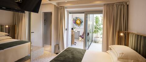 A hotel room with a bed, a TV, a window with curtains, and a view of the outside.