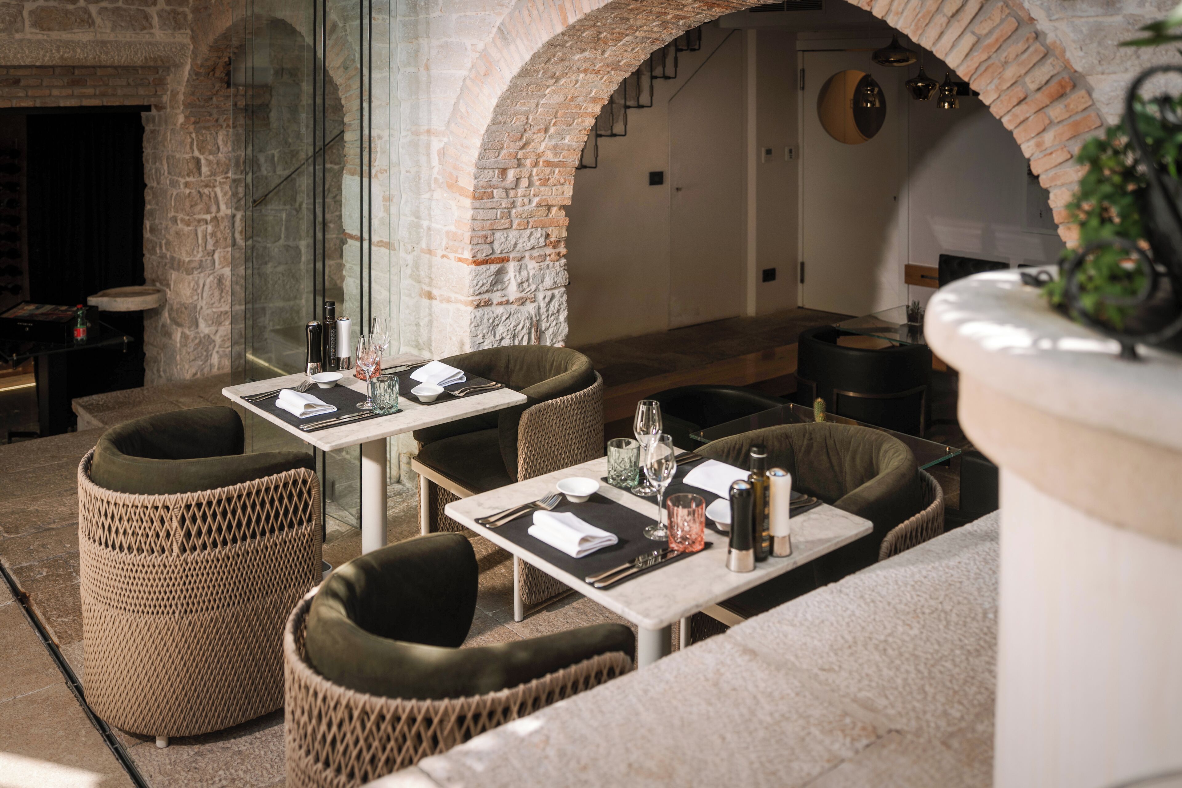An outdoor dining area with wicker furniture and stone walls.
