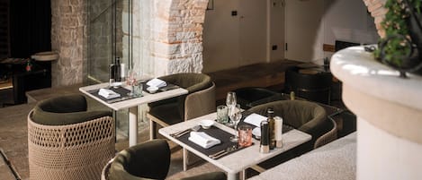 An outdoor dining area with wicker furniture and stone walls.