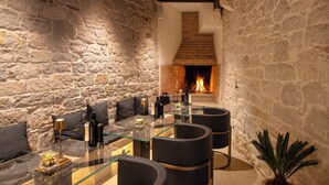 Une pièce aux murs de pierre, dotée d’une cheminée, d’une table à manger au plateau en verre et d’un mobilier moderne.