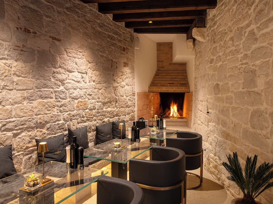 Una habitación con paredes de piedra, una chimenea, una mesa de comedor de vidrio y muebles modernos.