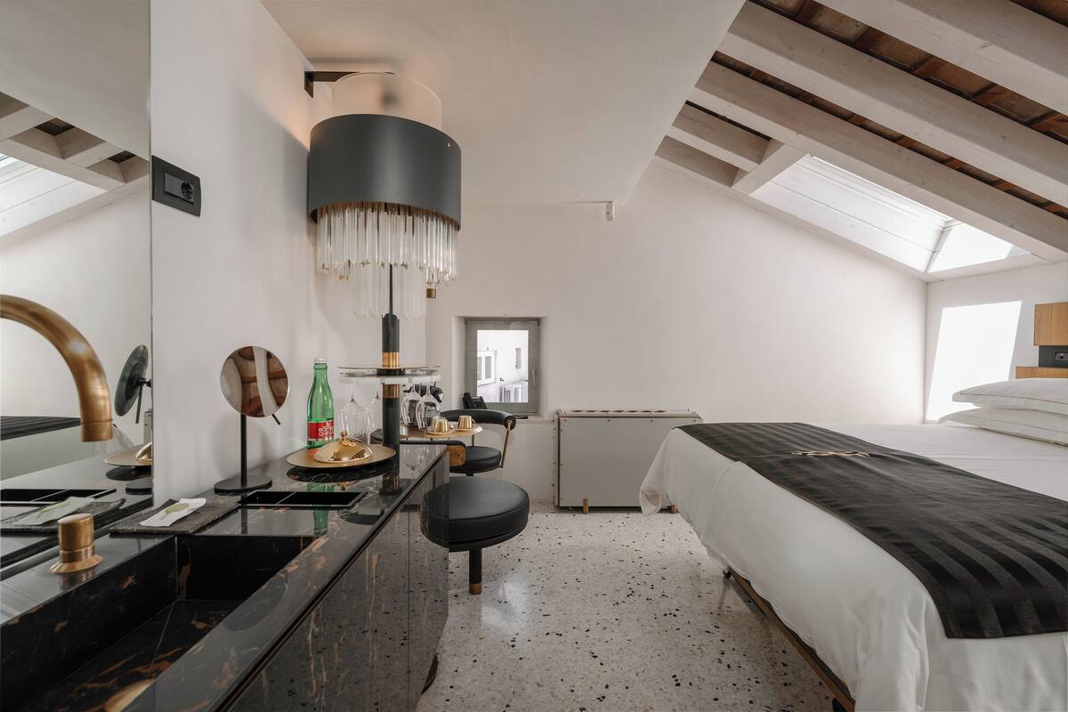Un dormitorio moderno con tragaluz, una cama grande, un escritorio con espejo y una lámpara colgante.