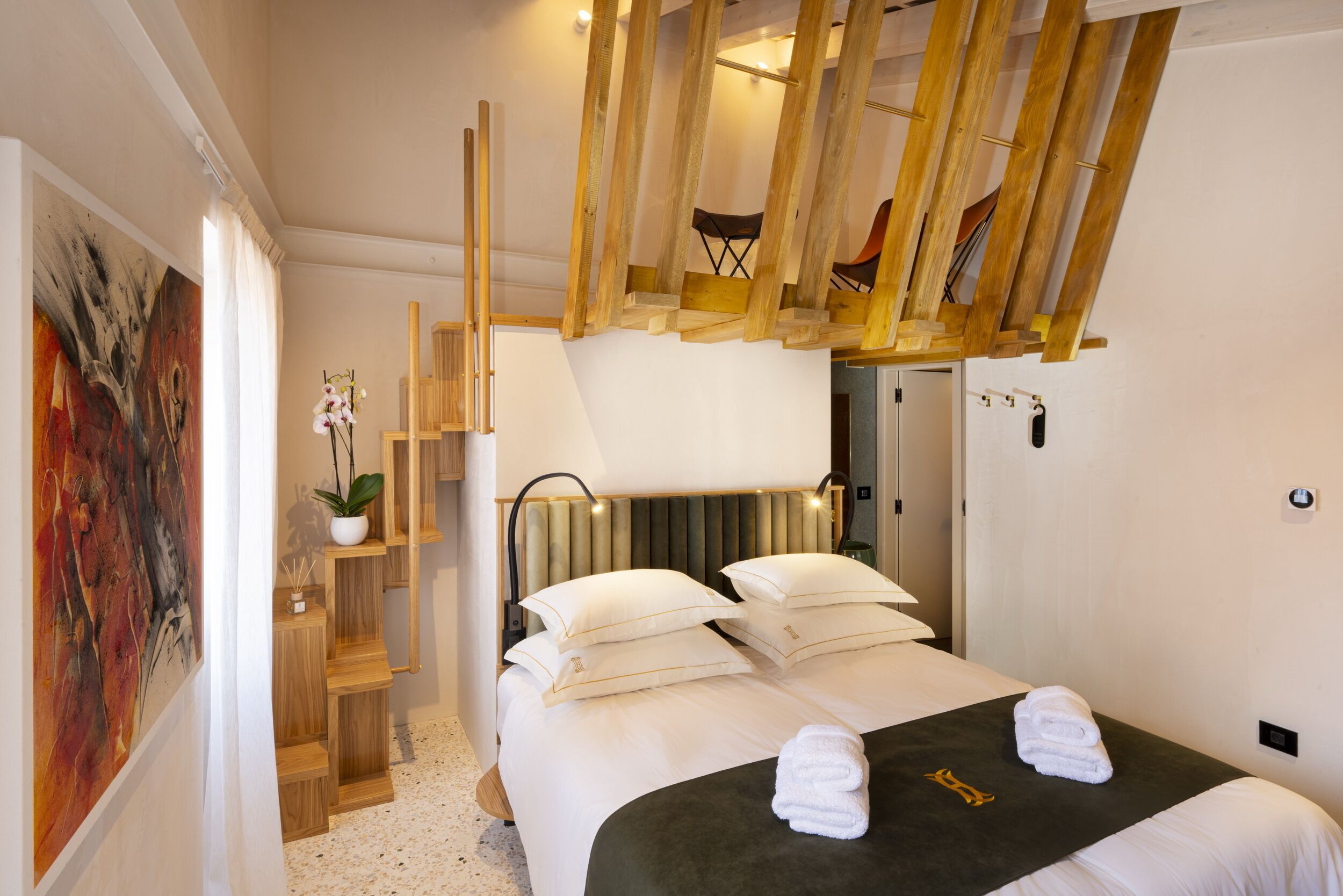 A modern hotel room with a large bed, wooden headboard, and a unique ceiling design.