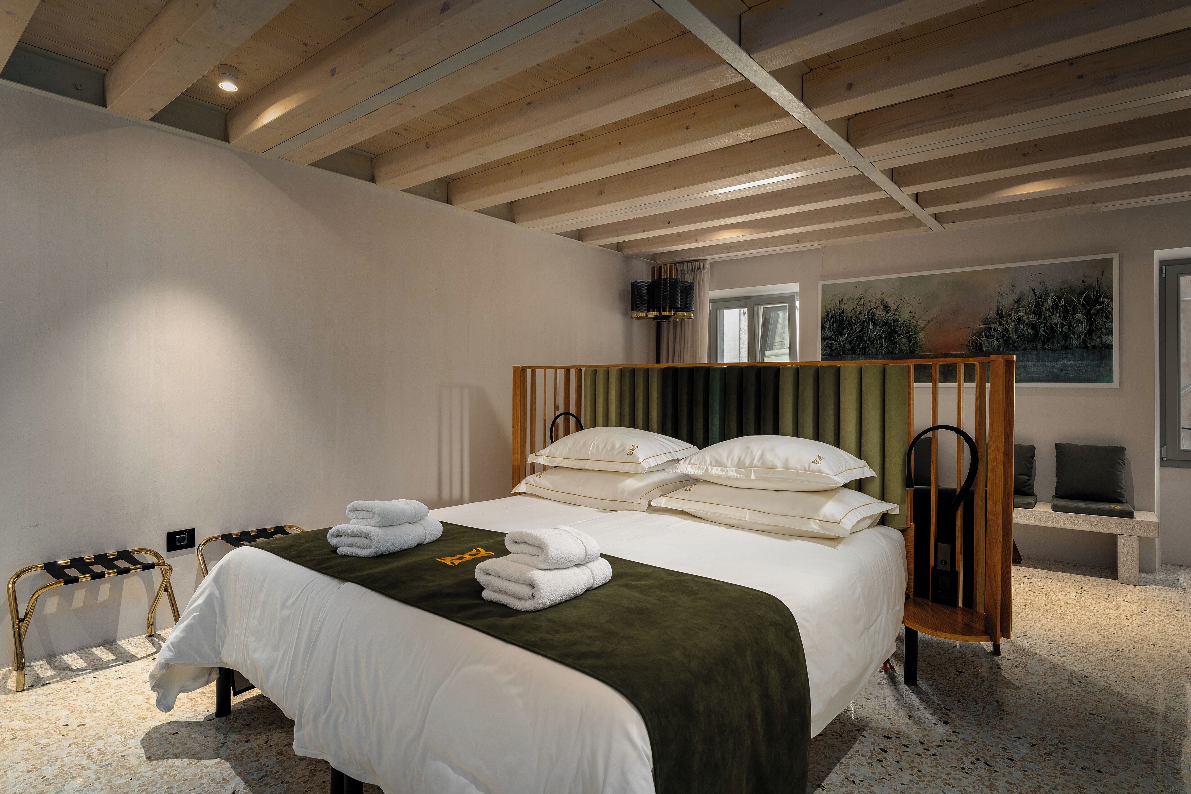 Ein Hotelzimmer mit einem großen Bett, einer Bank und Blick ins Freie.