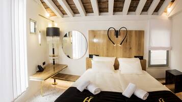 Una habitación de hotel moderna con cabecera de madera, un espejo redondo grande, una mesita de noche con lámpara, y camas ordenadas con toallas.