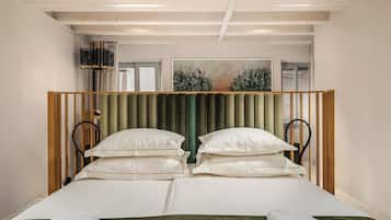 Una cama doble con cabecera verde, sábanas blancas y dos almohadas.