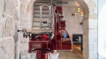 Una máquina de espresso roja con la marca "Berkel" en una habitación de paredes de piedra con un arco de entrada al fondo.