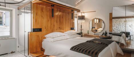 Un dormitorio moderno con cabecera de madera, una cama grande con ropa blanca, una mesita de noche con lámpara y un espejo grande.