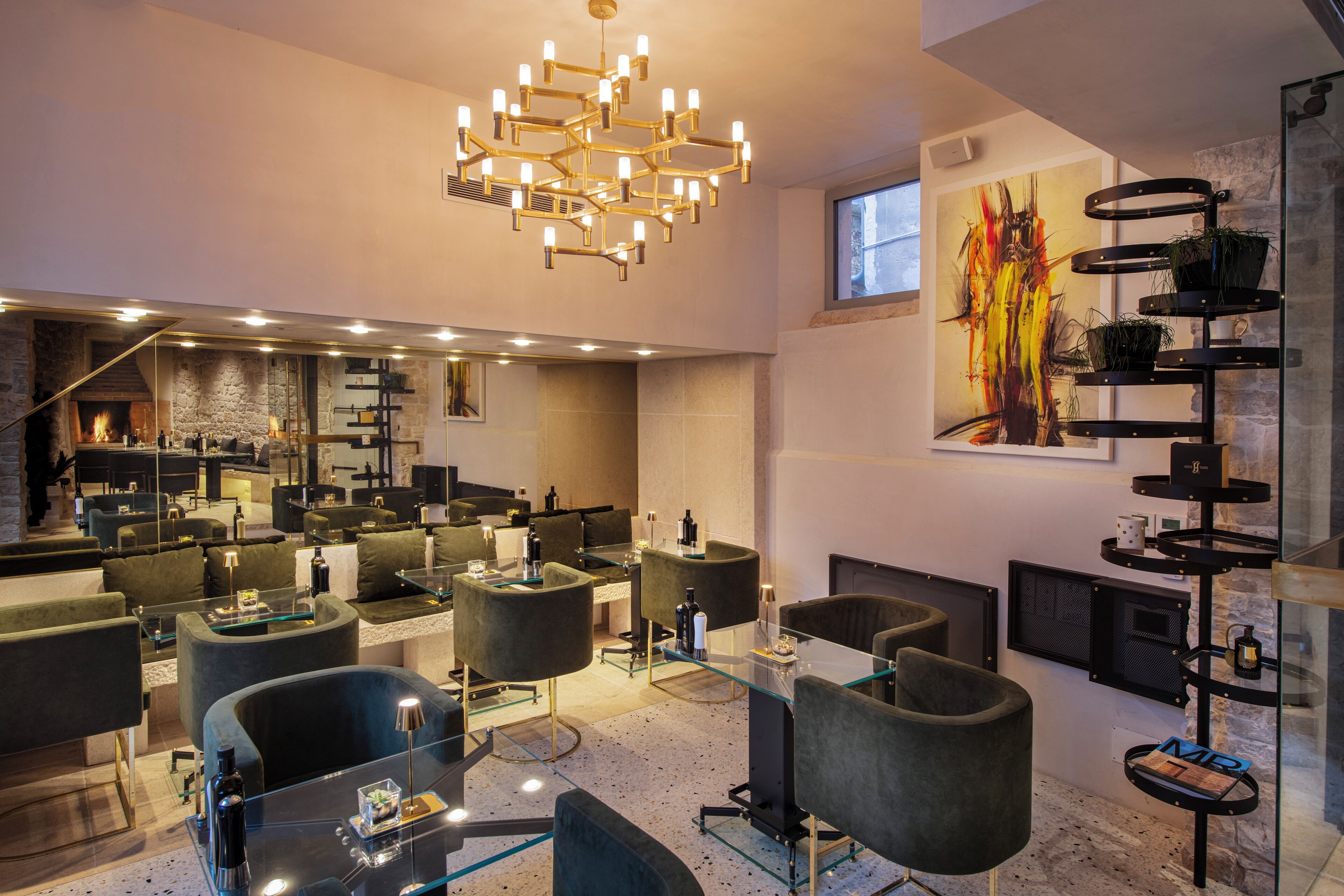 Een moderne hotellobby met een centraal zitgedeelte, een open haard en een groot abstract schilderij aan de wand.